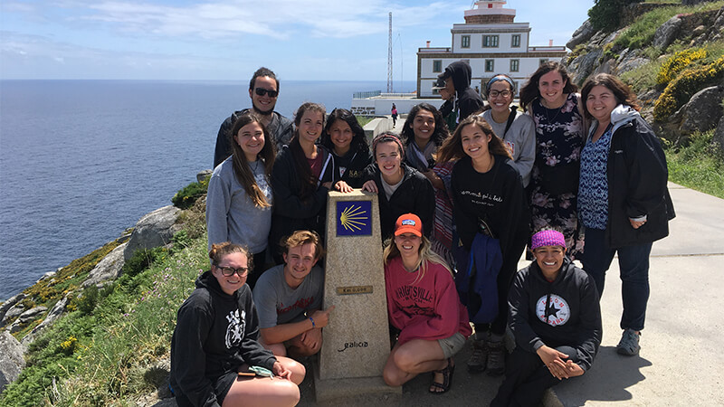 Students pose around a stone plinth marking the camino de santiago.