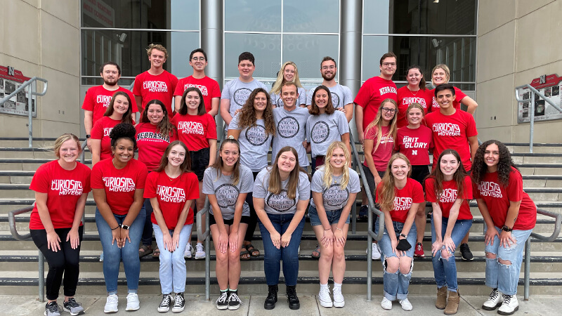 Large group of student ambassadors pose on stairs.