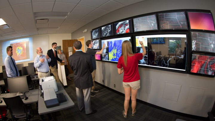 Clint Rowe, left, Professor of Earth & Atmospheric Sciences in the College of Arts and Sciences, describes the touch screen video wall.  Students demonstrated the wall during an open house for the newly remodeled Meteorology-Climatology Computer Lab in Bessey Hall.